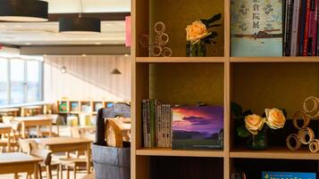 A library with bookshelves, a wooden table, and a vase with roses.