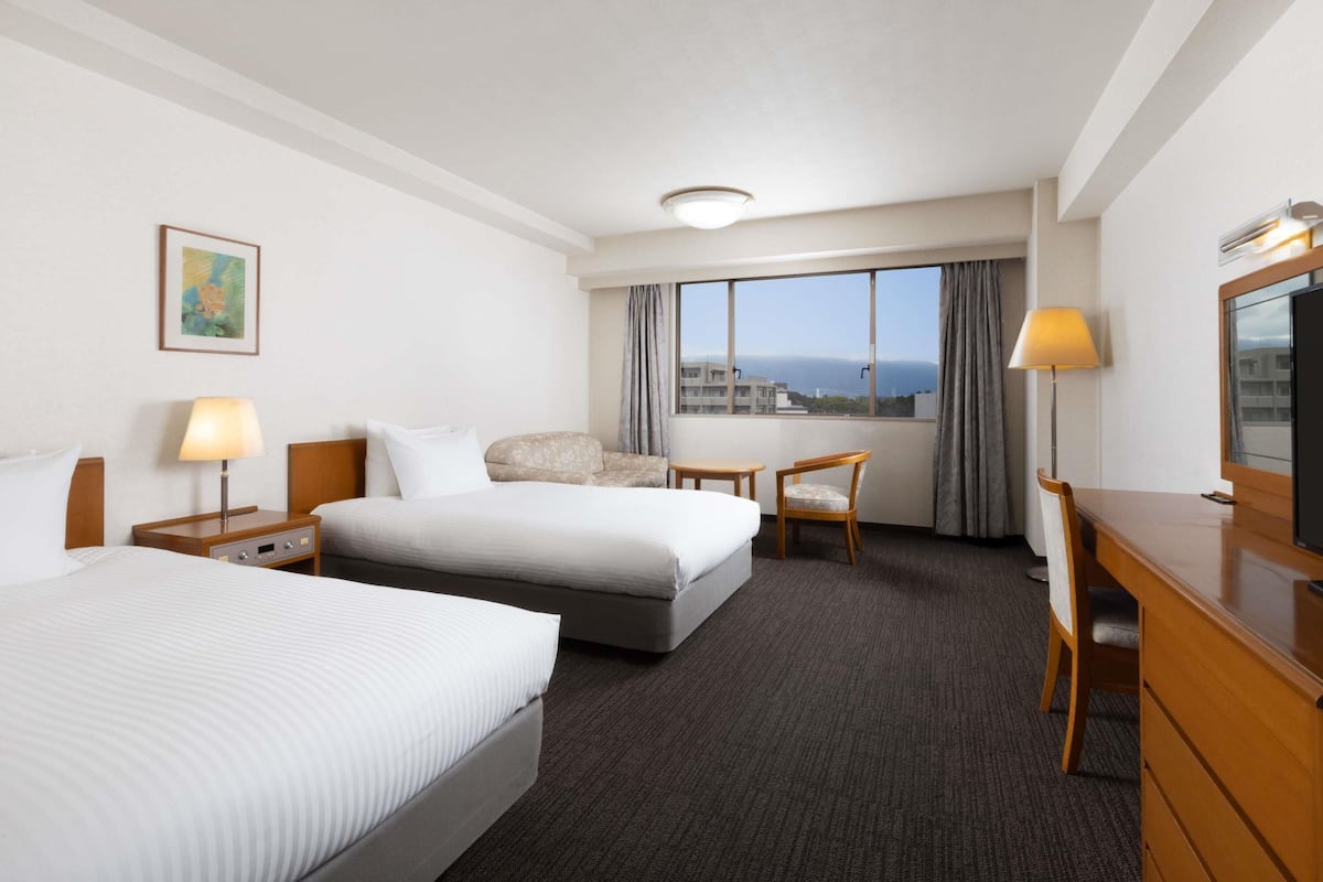 Ein Hotelzimmer mit Bett, Schreibtisch, Sessel, Fernseher und Fenster mit Blick.