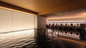 A modern indoor pool area with a wooden ceiling, tiled walls, and a wet floor reflecting the lights. - Grand Mercure Nara Kashihara (Kashihara)