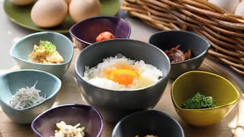 A variety of bowls containing different food items, including rice, eggs, and vegetables, arranged on a wooden surface.
