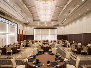 Un salón de conferencias con varias mesas, sillas y una lámpara de araña grande.