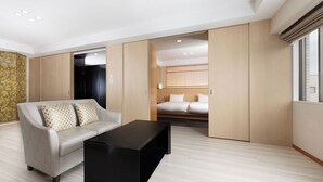 A modern hotel room with a sofa, a black coffee table, a bed with white bedding, and a sliding door closet. - Grand Mercure Nara Kashihara (Kashihara)