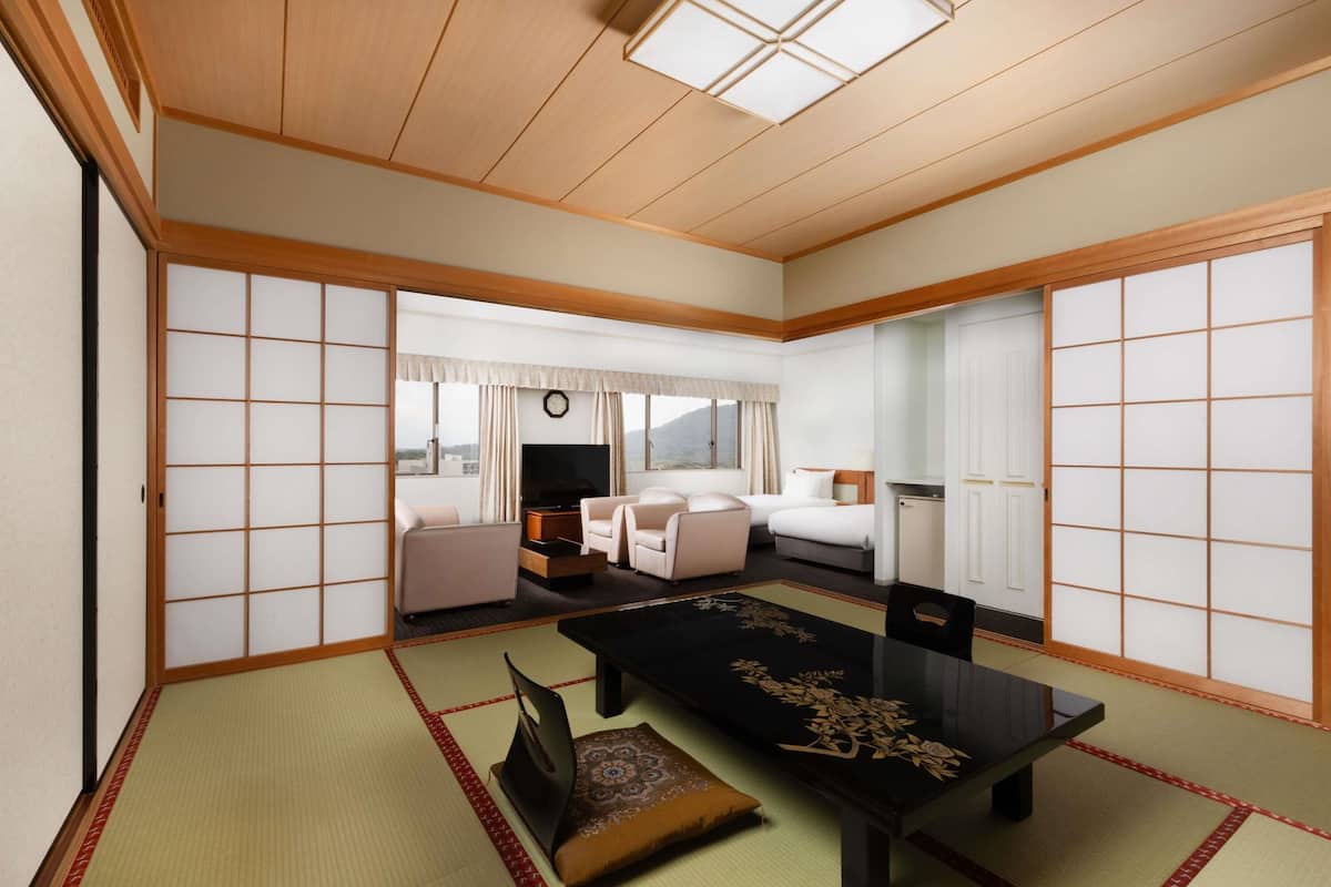 Ein traditionell japanisch gestaltetes Hotelzimmer mit Tatami-Böden, einem niedrigen Tisch und verschiebbaren Türen.