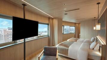 Ein modernes Hotelzimmer mit einem großen Bett, einem Fernseher und Blick auf die Stadt.