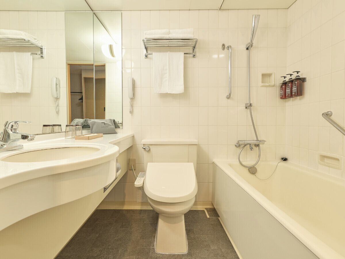 A modern bathroom with a toilet, two sinks, a bathtub, and a shower.