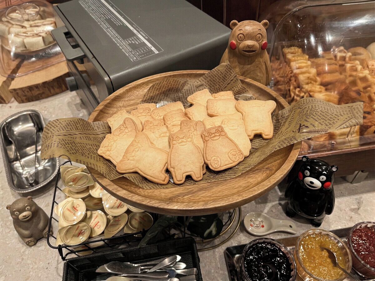 Una bandeja de galletas con forma de oso, una figurita de oso y frascos de mermelada.
