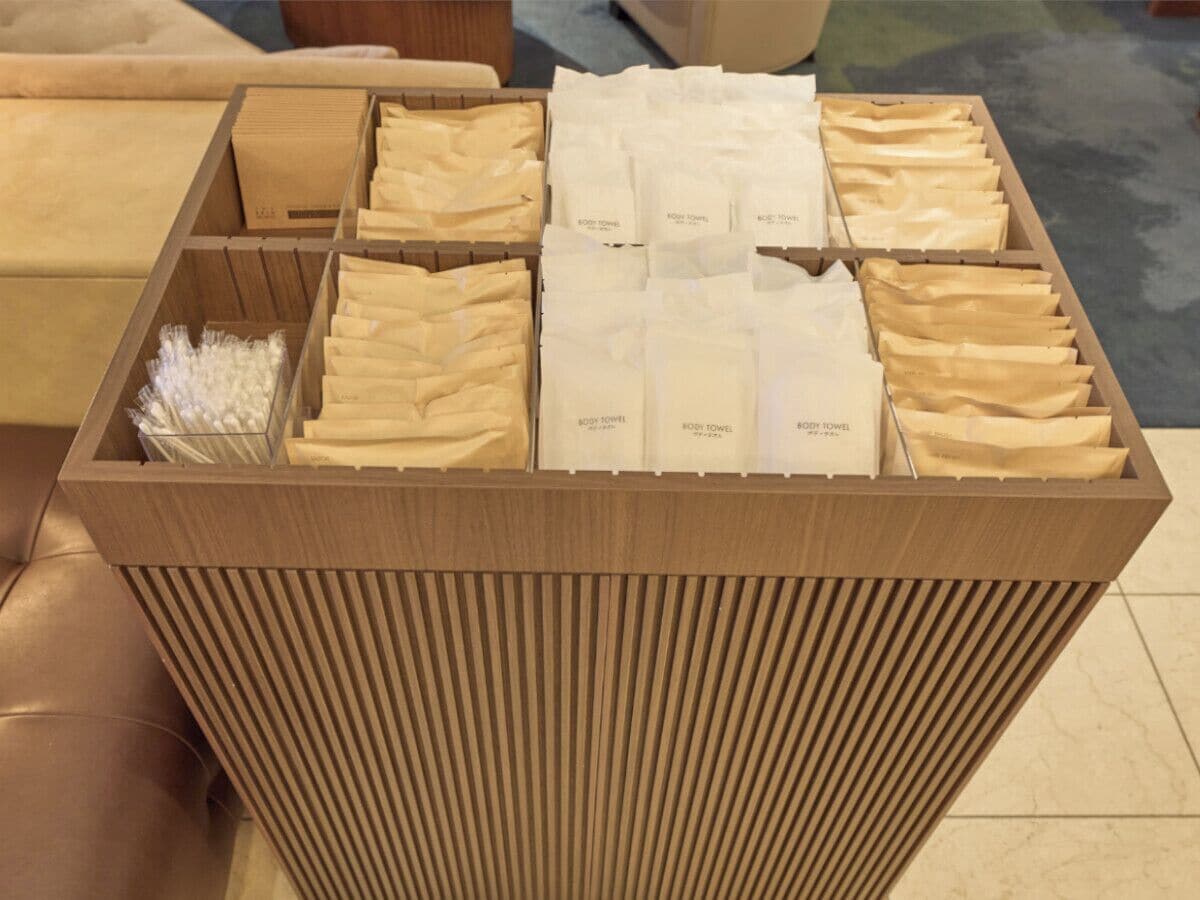 A wooden box with compartments containing neatly folded white towels labeled "BODY TOWEL."