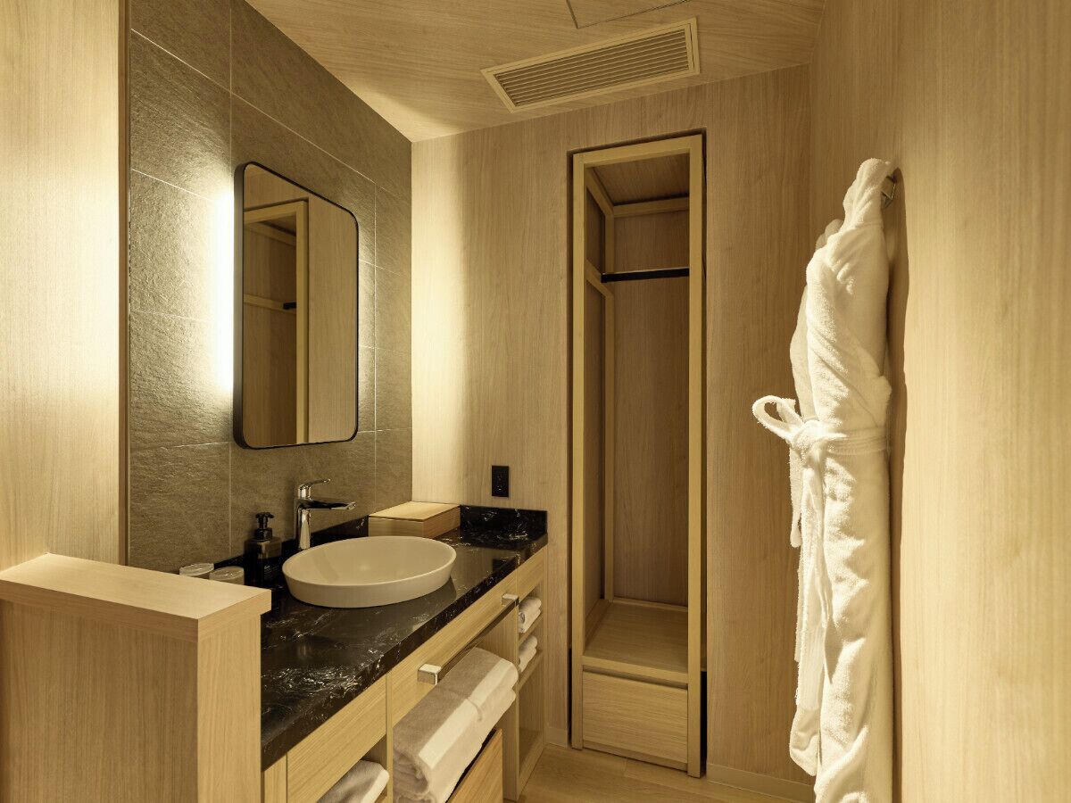 A modern bathroom with a wooden vanity, a large mirror, a sink, and a walk-in shower.