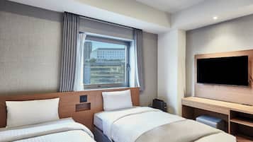 A hotel room with two beds, a TV, a desk, and a window with curtains.
