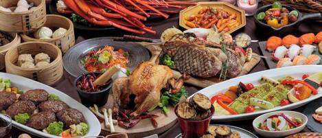 Variedad de platos, incluyendo mariscos, carnes a la parrilla y verduras, que sugiere una amplia selección de comidas.