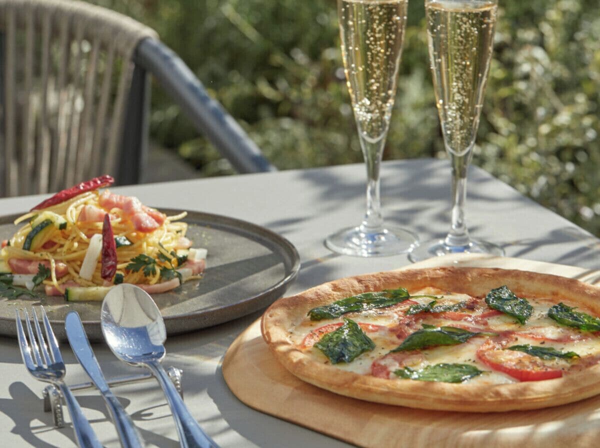 Ett bord med en pizza, en sallad och två glas champagne.