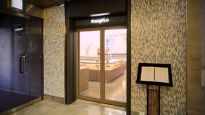 A hotel entrance with a reception desk, a glass door, and a menu stand. - Takamatsu Tokyu REI Hotel (Takamatsu)