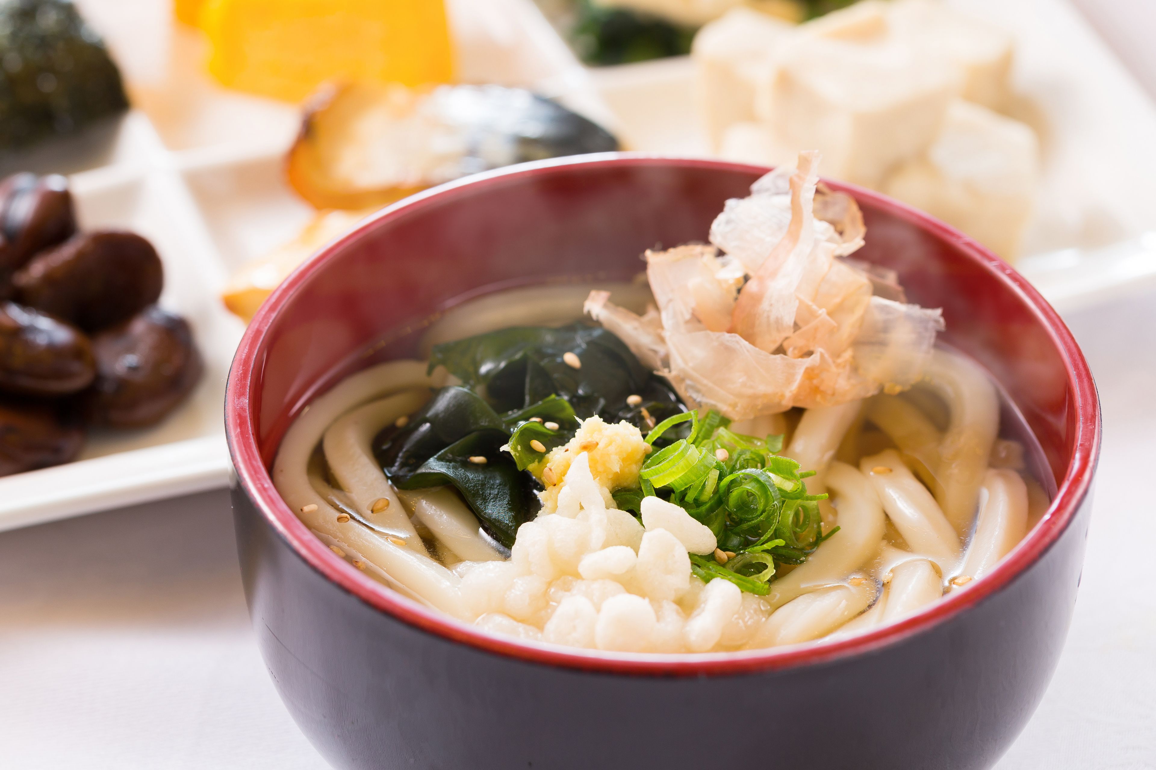 A bowl of ramen with toppings including seaweed, green onions, and a piece of fish.