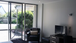 A modern room with a bed, a desk, a chair, and a television. - Pacific Park (Dunedin)