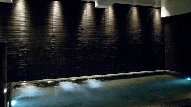Ein Wellnessbereich mit beheiztem Steinbad und dunkler Wandverkleidung.