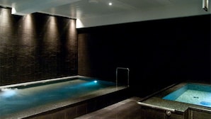 Ein Wellnessbereich mit einer großen Whirlwanne und einem kleineren Pool, beide mit integrierter Beleuchtung.