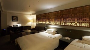 Ein Hotelzimmer mit einem großen Bett, einem Schreibtisch mit Stuhl, einem kleinen Tisch, einer Lampe und einer Wand mit Musterdesign.