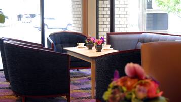 Un hall d’hôtel doté d’un espace détente avec des fauteuils confortables et une table ornée d’un vase de fleurs.