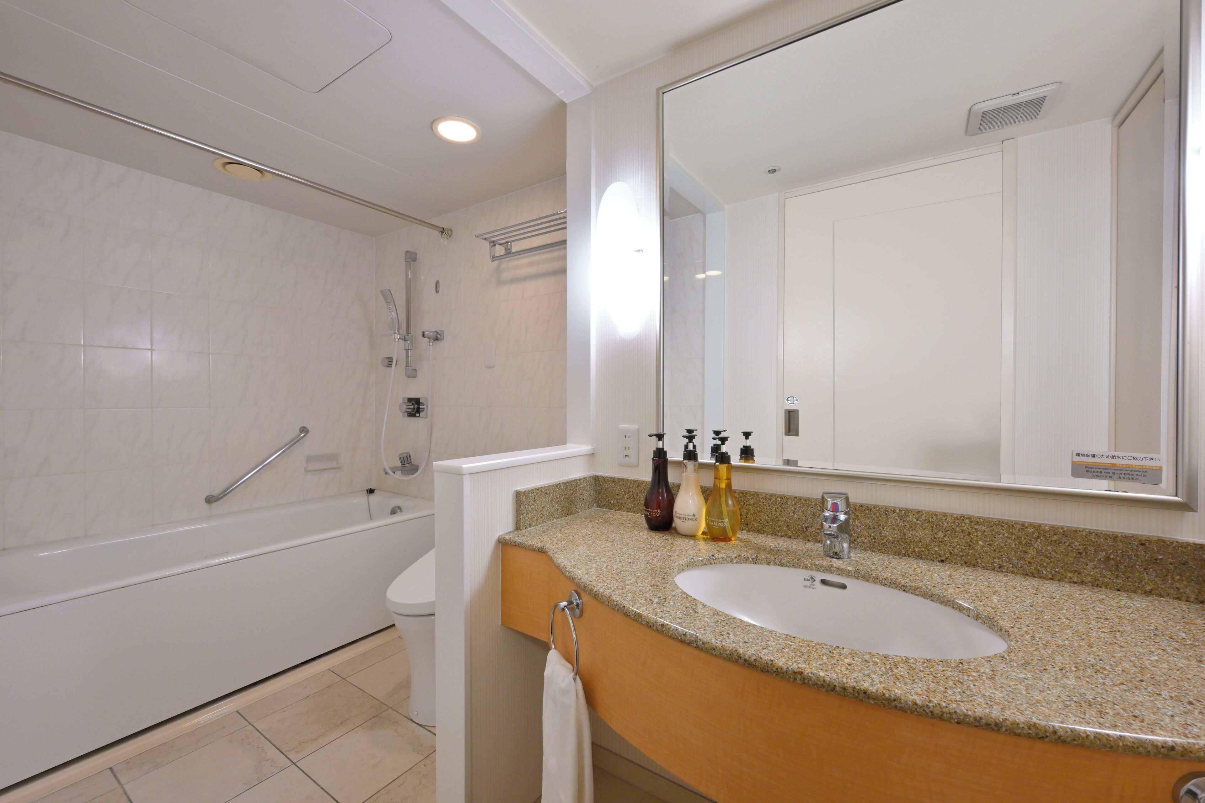 Un baño con bañera, lavamanos, espejo y artículos de aseo.