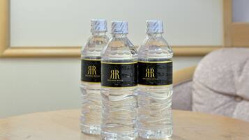 Tres botellas de agua transparente con etiquetas doradas y negras sobre una mesa redonda.