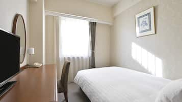 A hotel room with a bed, a desk with a TV, a chair, a window with curtains, and a framed picture on the wall.