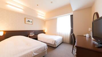 A hotel room with two beds, a desk with a computer, a TV, and a window with curtains.