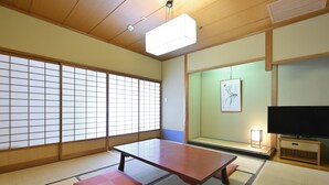 A traditional Japanese room with tatami flooring, a low table, cushions, sliding doors, a television, and a framed artwork on the wall. - Rihga Hotel Zest Takamatsu (Takamatsu)