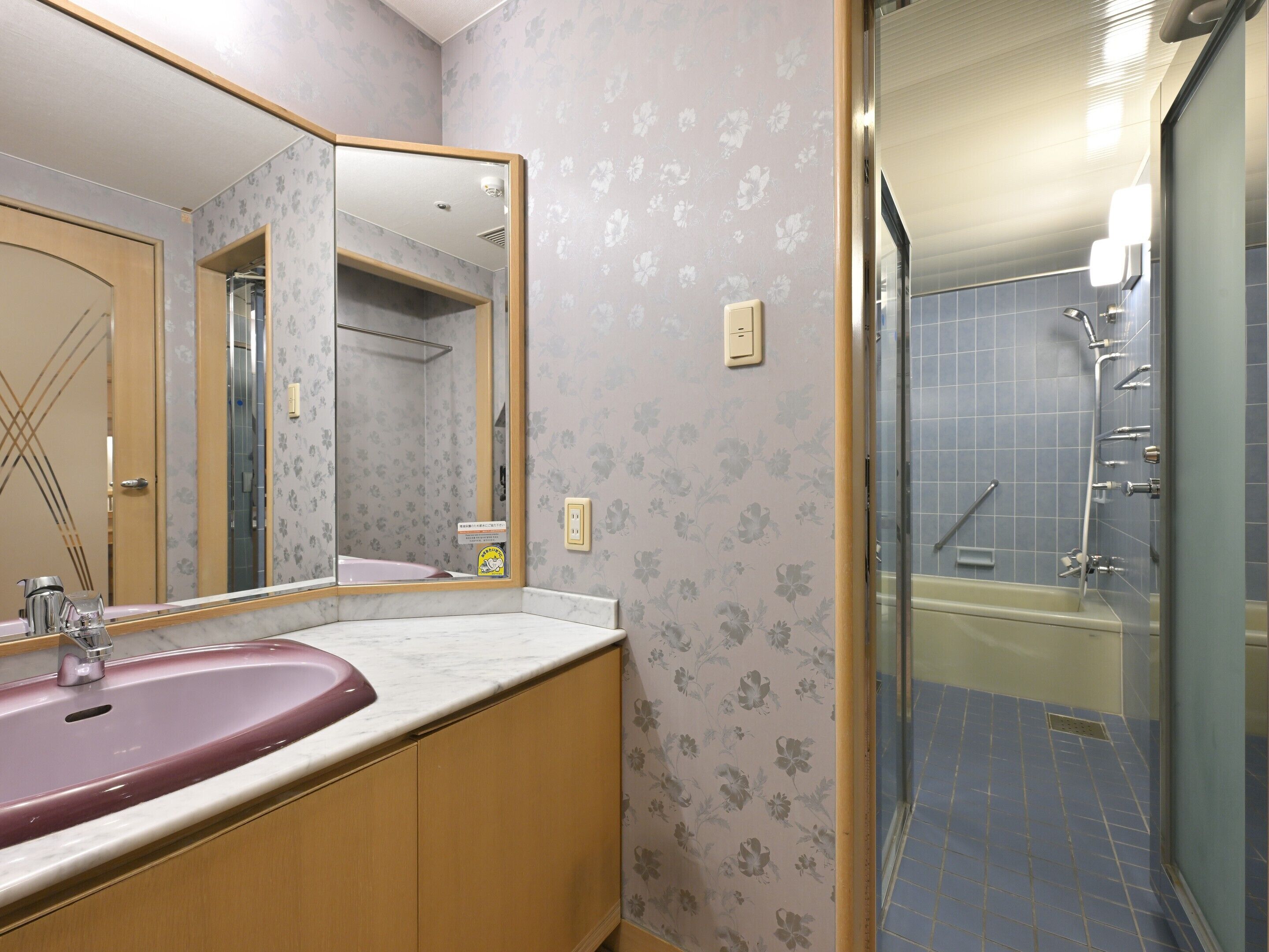 A bathroom with a pink sink, a mirror, and a shower area.