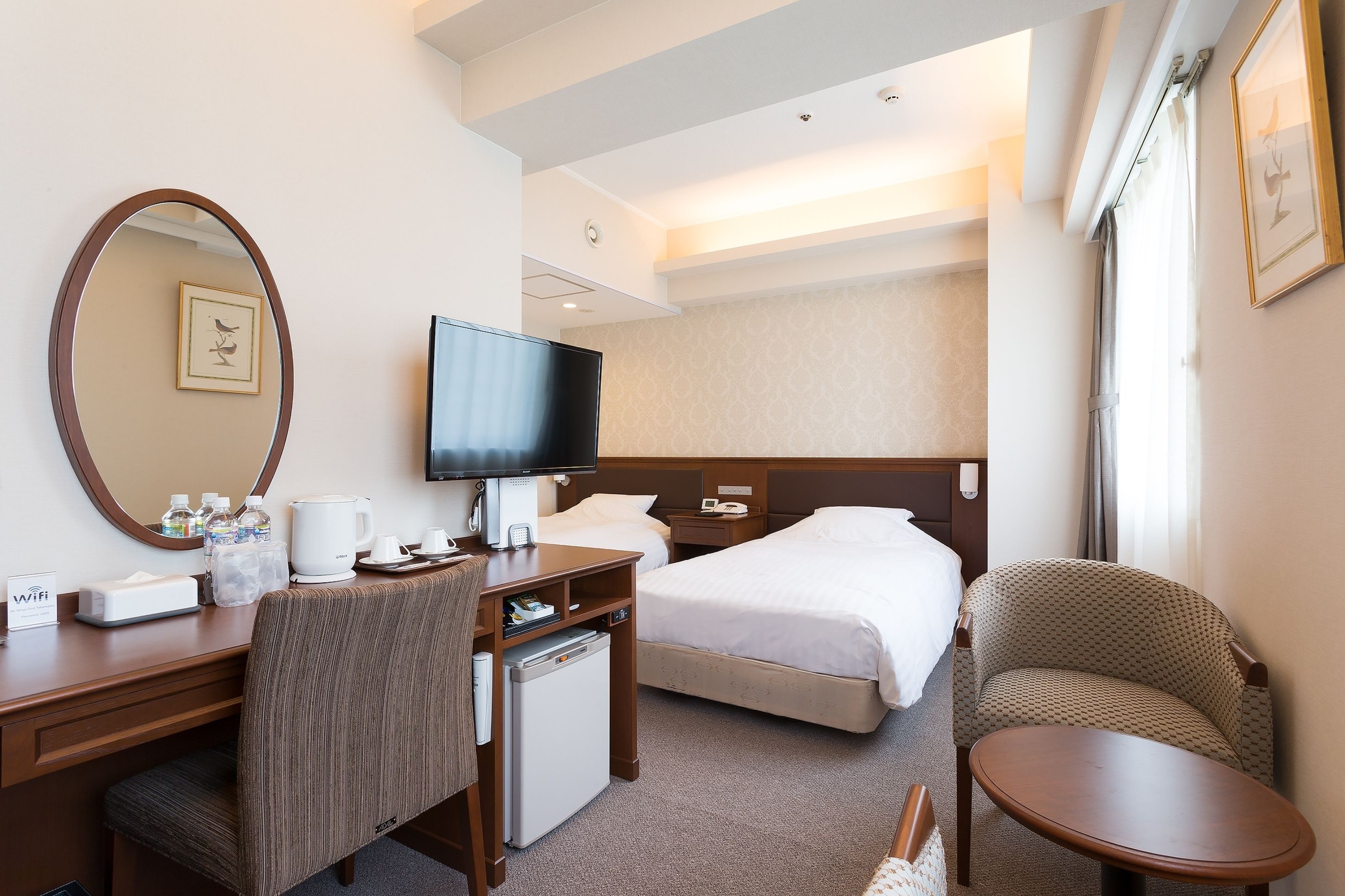 Une chambre d’hôtel comprenant un lit, un bureau avec un ordinateur, une chaise, une petite table et un téléviseur.