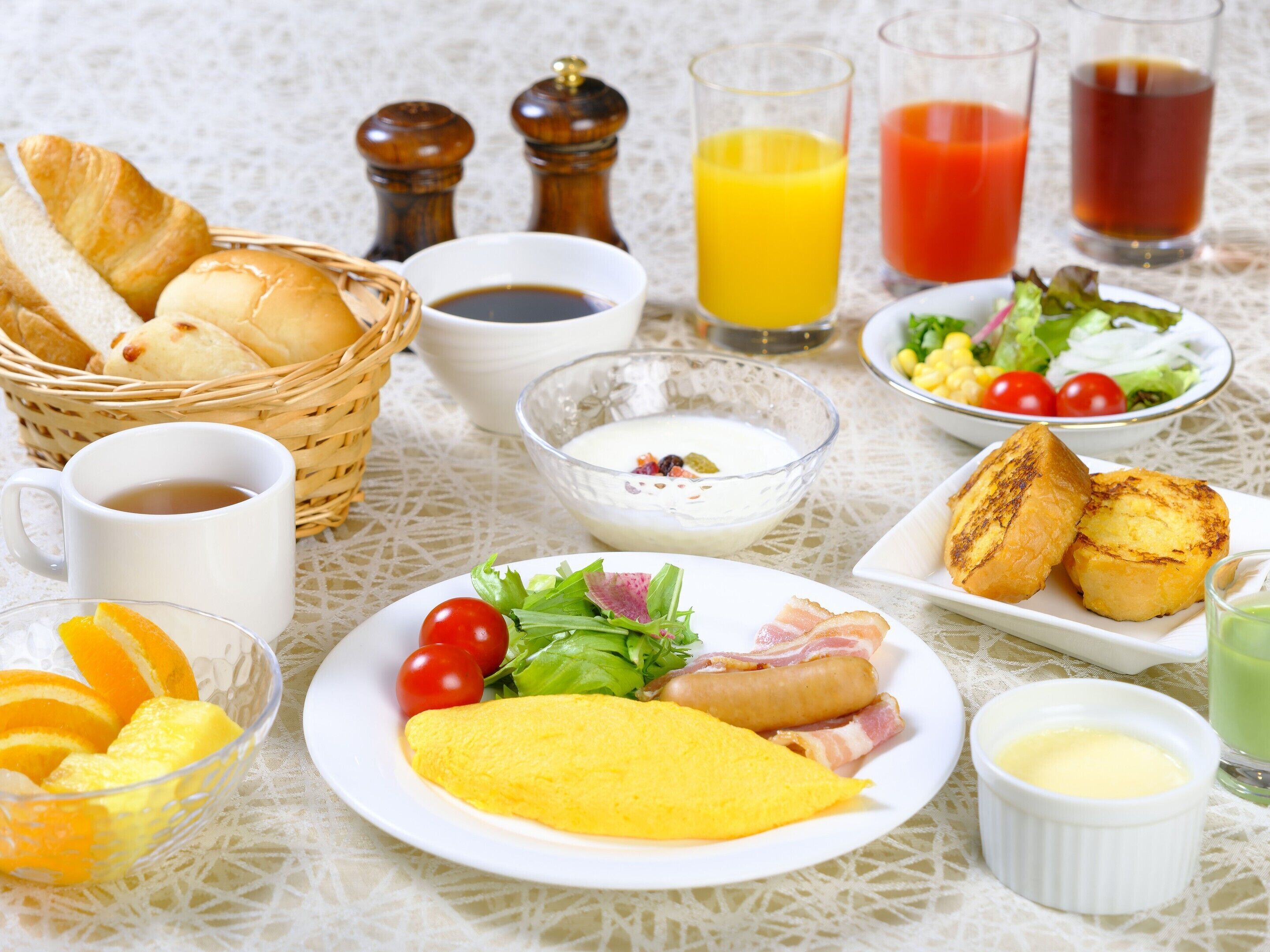 Una mesa de desayuno con pan, huevos, tocino, tomates y una ensalada.
