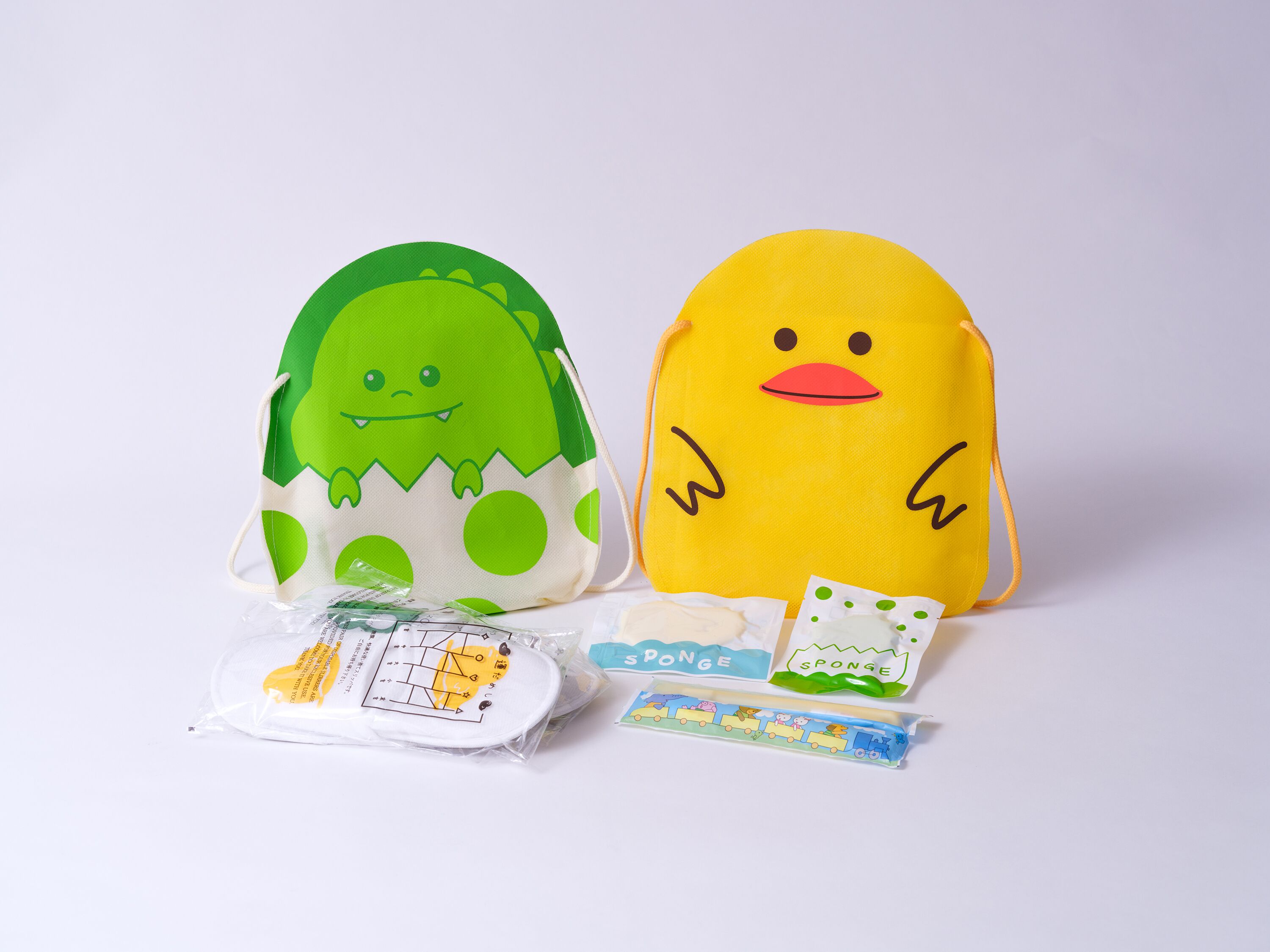 Two plush toys, one green and one yellow, with a small package and a toy train set in front.