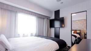 Ein modernes Hotelzimmer mit einem großen Bett, einem wandmontierten Flachbildfernseher, einem Schreibtisch und einem Spiegel.