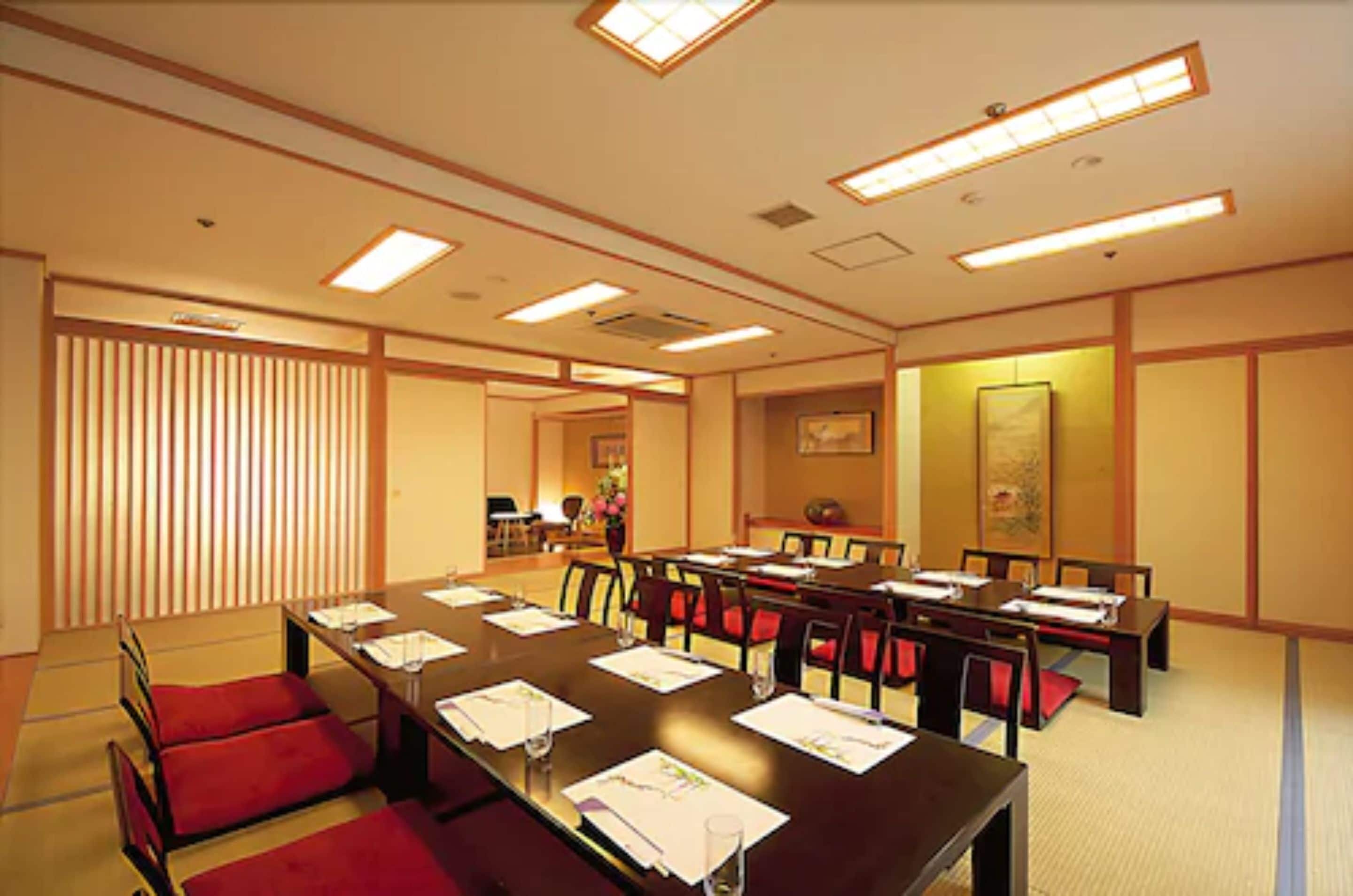 A conference room with a long table, red chairs, and a traditional Japanese aesthetic.