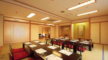 A conference room with a long table, red chairs, and a traditional Japanese aesthetic.