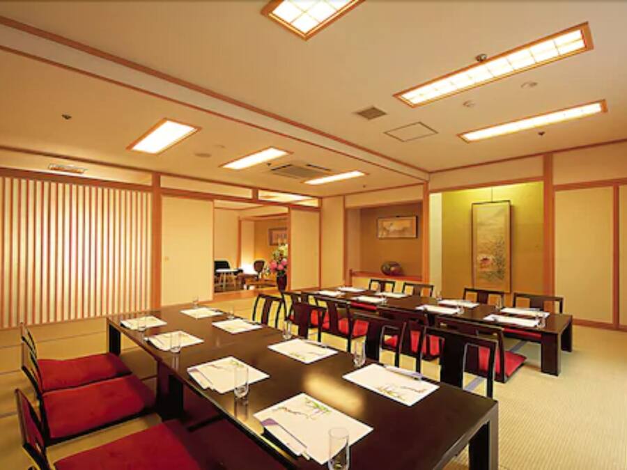 A conference room with a long table, red chairs, and a traditional Japanese aesthetic.