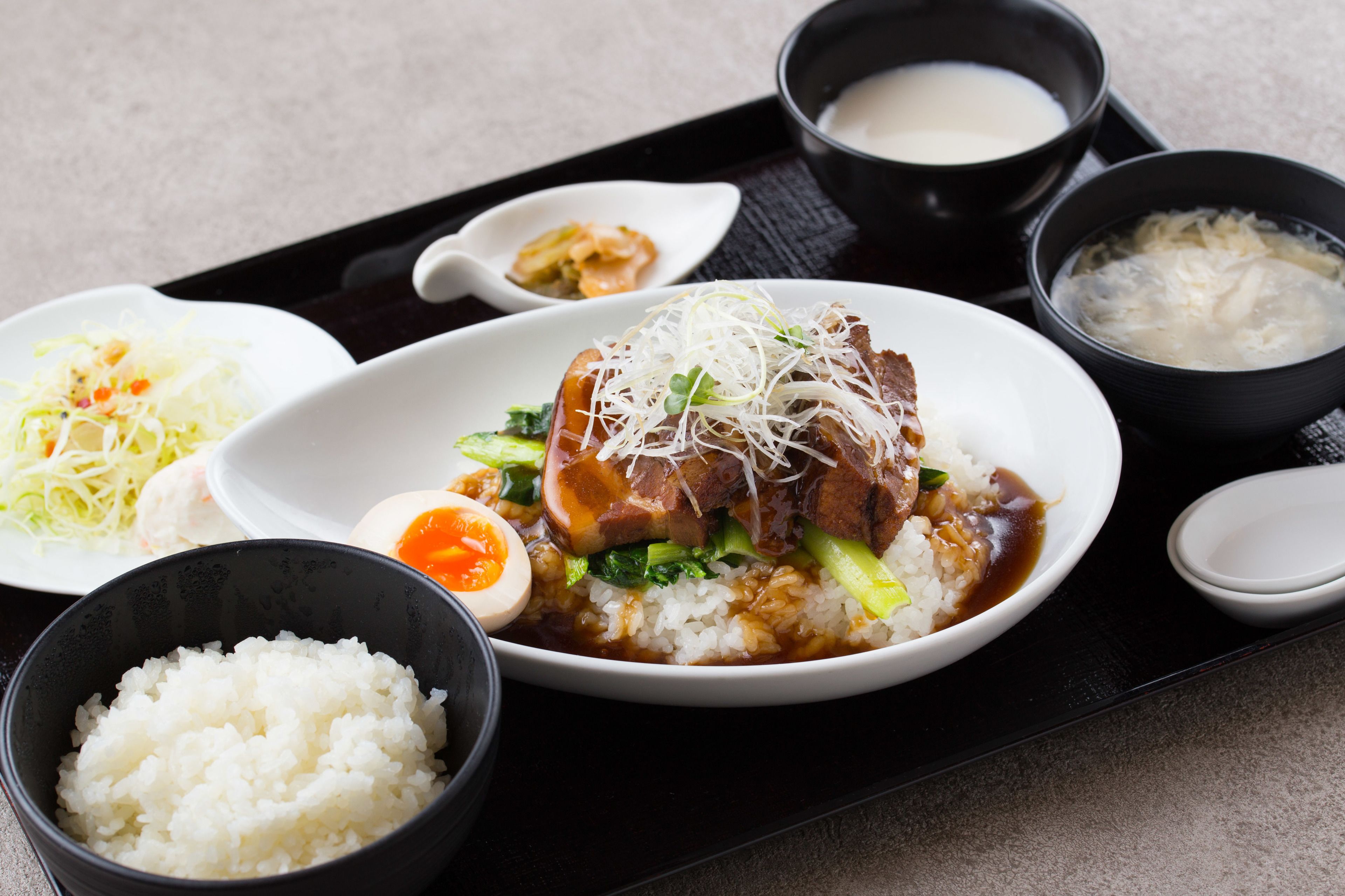 A meal with rice, meat, and vegetables, accompanied by small bowls of soup and condiments.