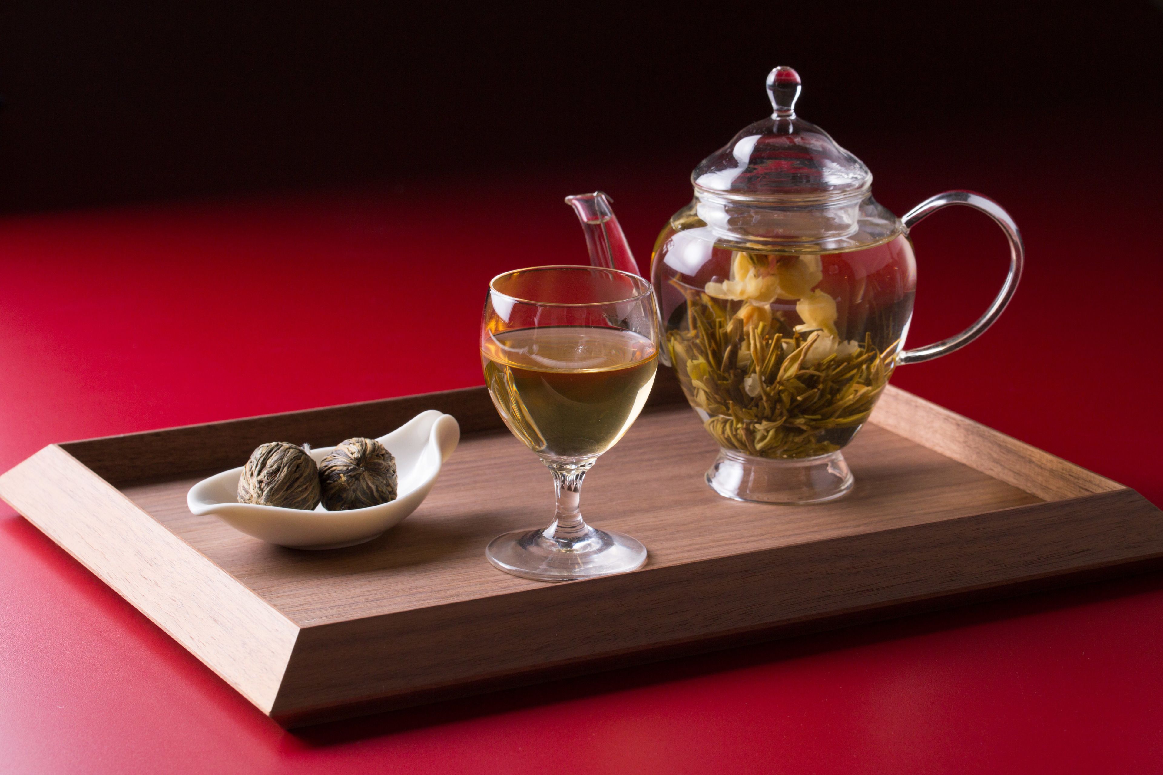 A tray with a teapot, a glass, and a small bowl containing tea leaves.
