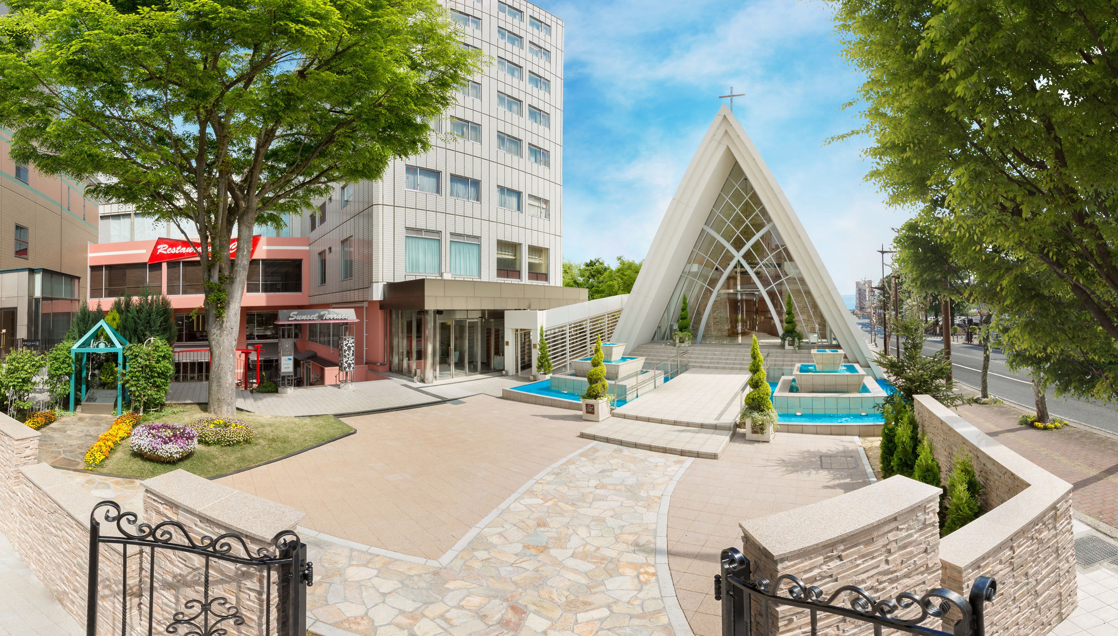 A modern building with a unique triangular design, a pool area, and a well-maintained garden.