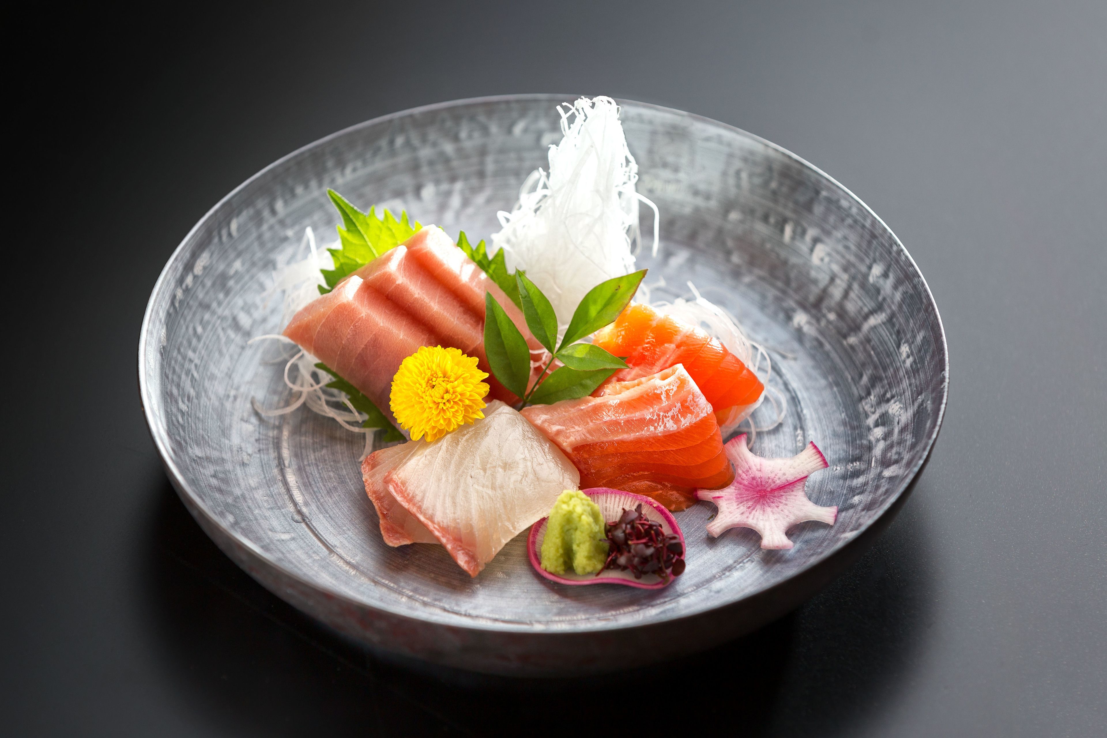 Een bord sushi met verschillende soorten vis en garneringen.