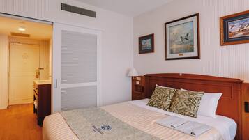 A hotel room with a bed, a nightstand, a lamp, and two framed pictures on the wall.