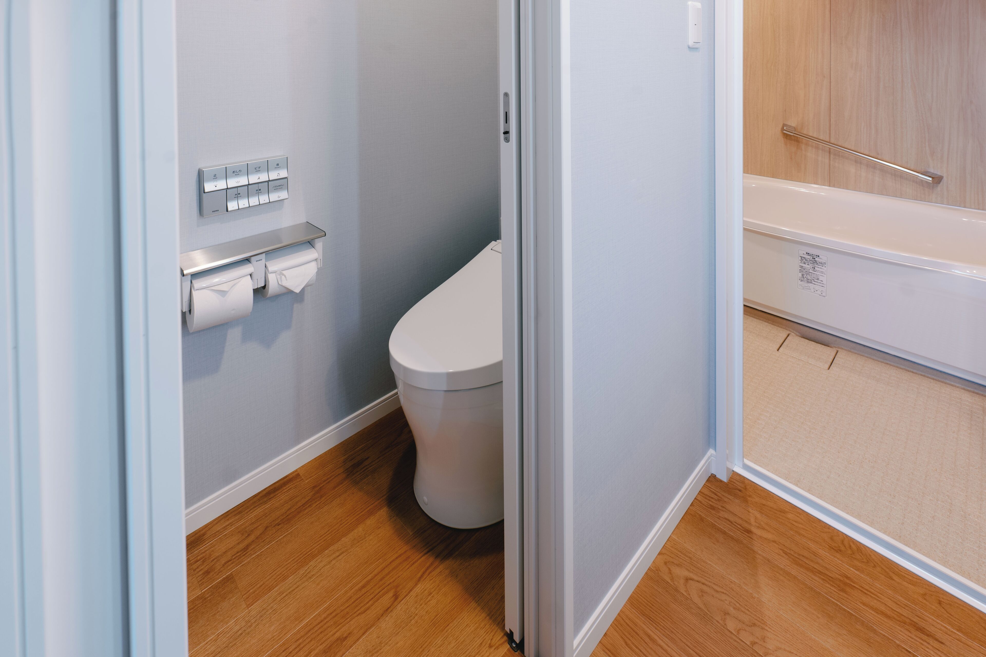 A bathroom with a toilet, a towel dispenser, and a shower area.