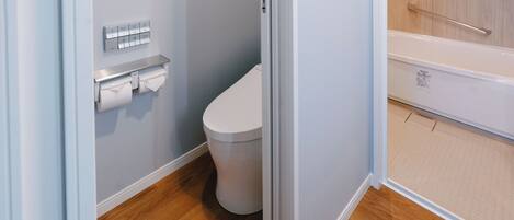A bathroom with a toilet, a towel dispenser, and a shower area.