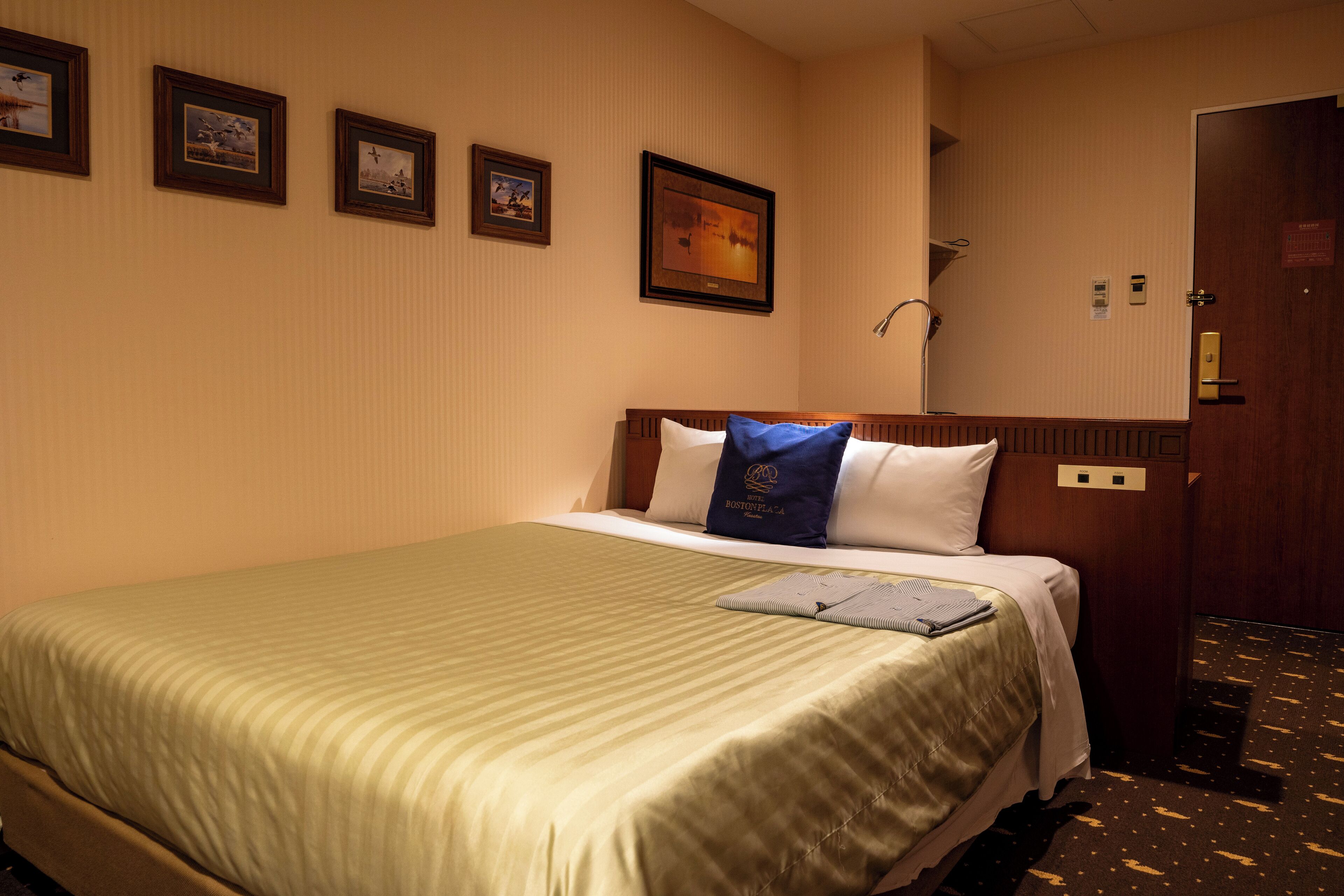 Une chambre d’hôtel avec un lit, une table de chevet, un miroir et une porte.