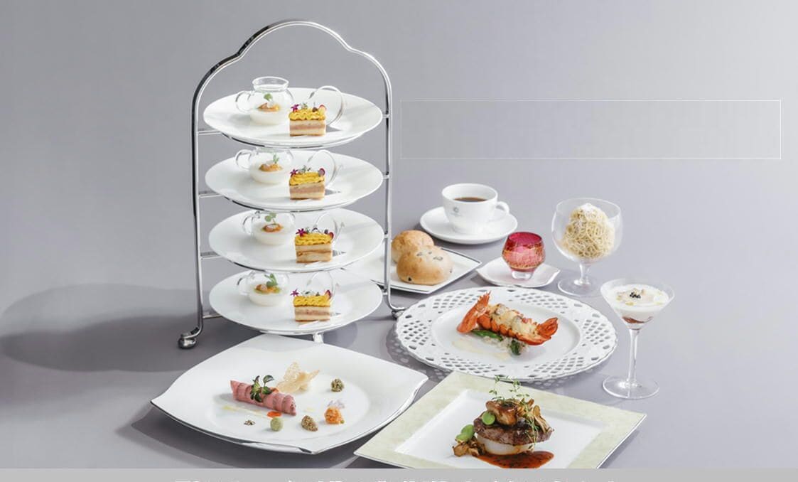 Un soporte escalonado para postres con diversas pastelerías y una taza de café sobre una mesa.