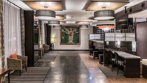 Eine moderne Hotelhalle mit einer langen Rezeption, einer Sitzecke und einem großen Gemälde an der Wand.