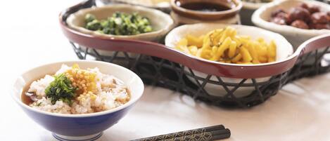 A variety of dishes in bowls and a basket, including rice, noodles, and dumplings, with chopsticks placed in front.