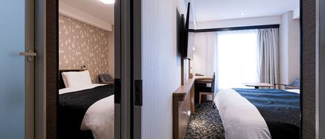 A hotel room with two beds, a desk, a TV, and a window with curtains.