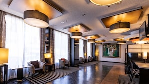 Eine moderne Lobby mit Marmorboden, einer Sitzecke mit gemusterten Sesseln und großen Pendelleuchten.