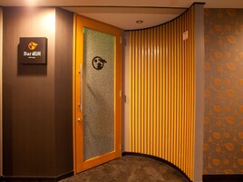 A hotel corridor with a wooden door, a sign for 'Bar', and patterned wallpaper.