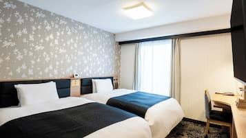 Ein Hotelzimmer mit zwei Betten, einem Schreibtisch, einem Stuhl, einem Fenster mit Vorhängen und einer Deckenleuchte.